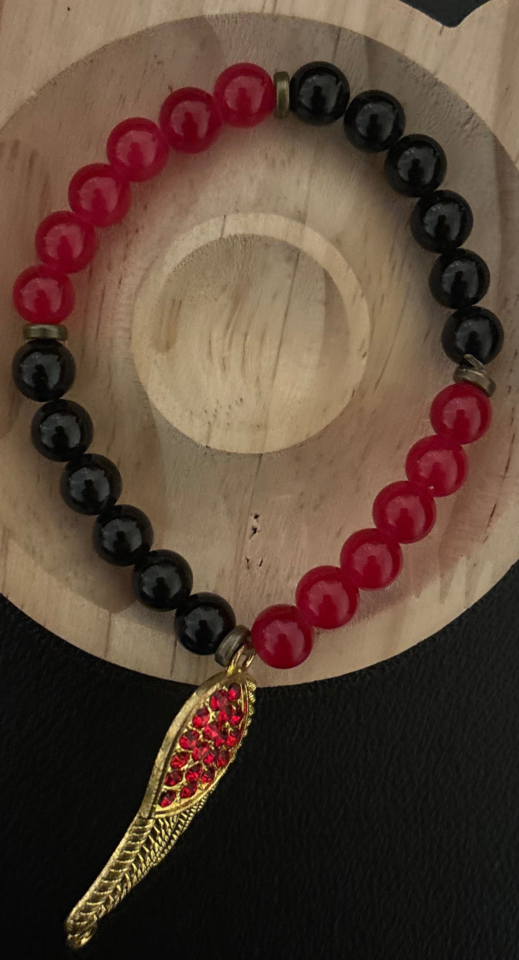 Red and black bracelet with a feather charm